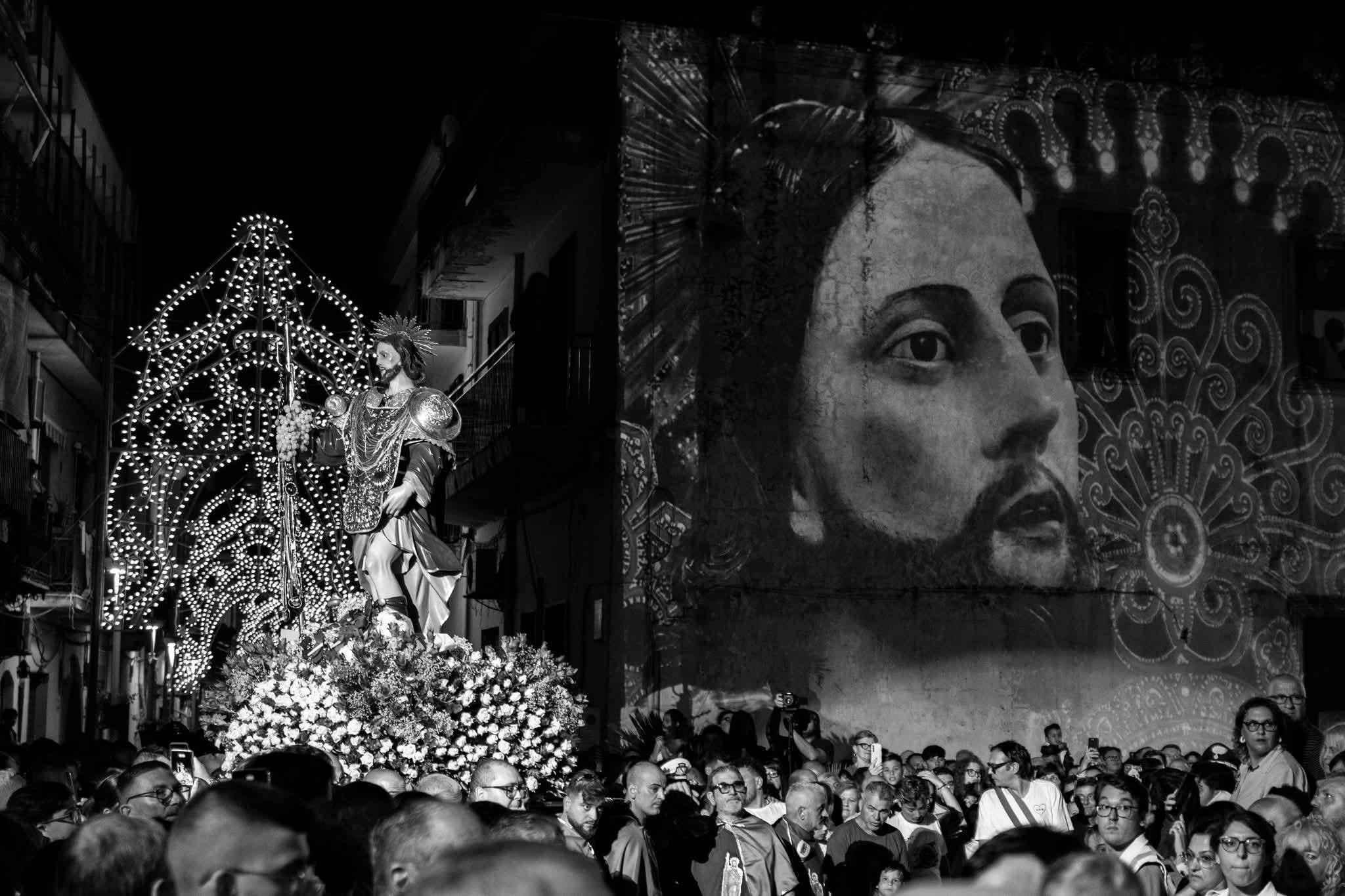 San Rocco pronto ad essere portato in processione — l'immagine votiva proiettata alle sue spalle